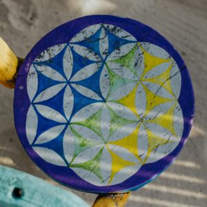 Colorful geometric pattern on a wooden stool against sandy beach backdrop.